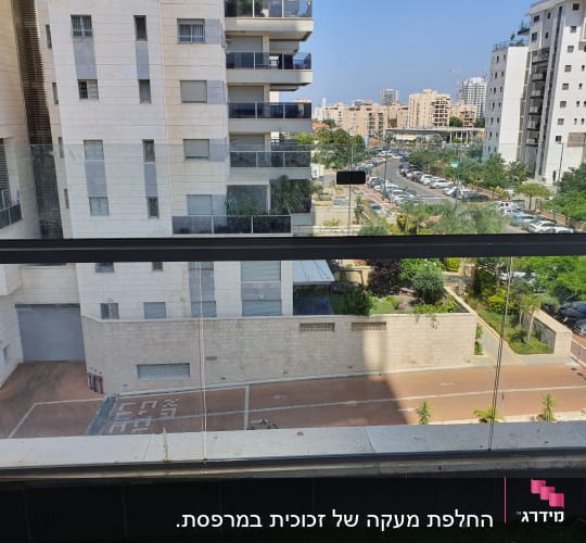 מעקה זכוכית במרפסת עם נוף עירוני